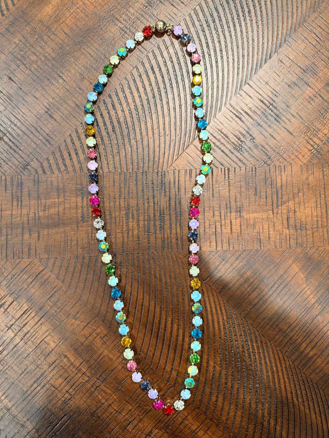 Multicolor round-stone necklace in gold-tone settings, upright with clasp at the top