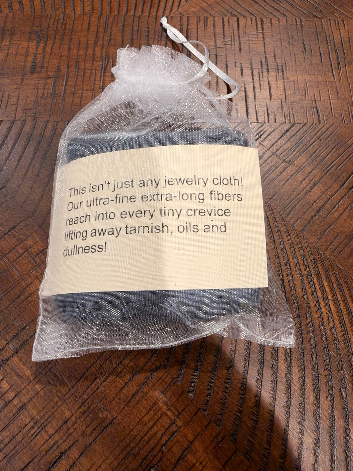 Jewelry cleaning cloth packaged in a white drawstring pouch with its care-product label