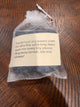 Jewelry cleaning cloth packaged in a white drawstring pouch with its care-product label