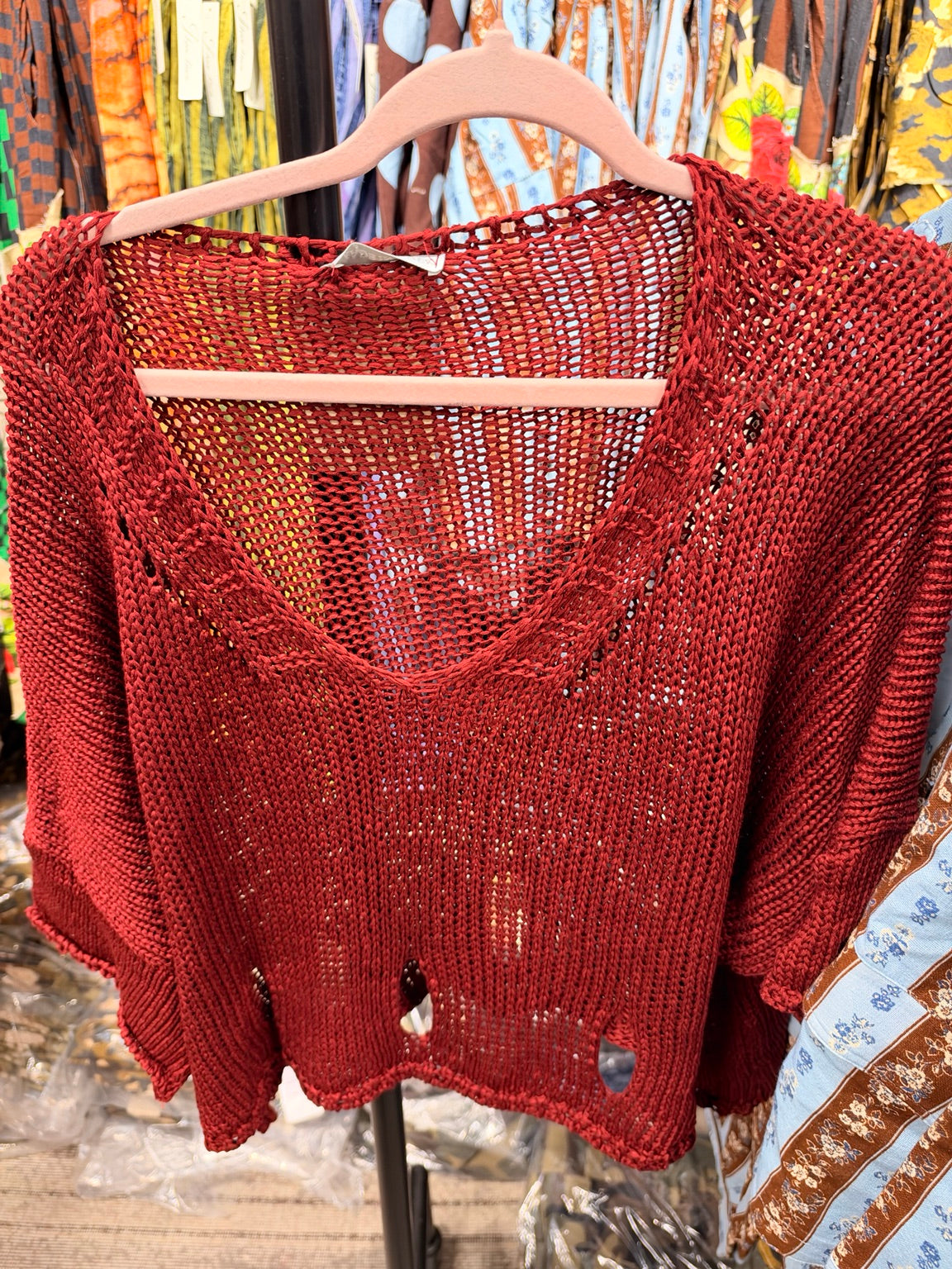 Red open knit V-neck sweater with distressed hem details