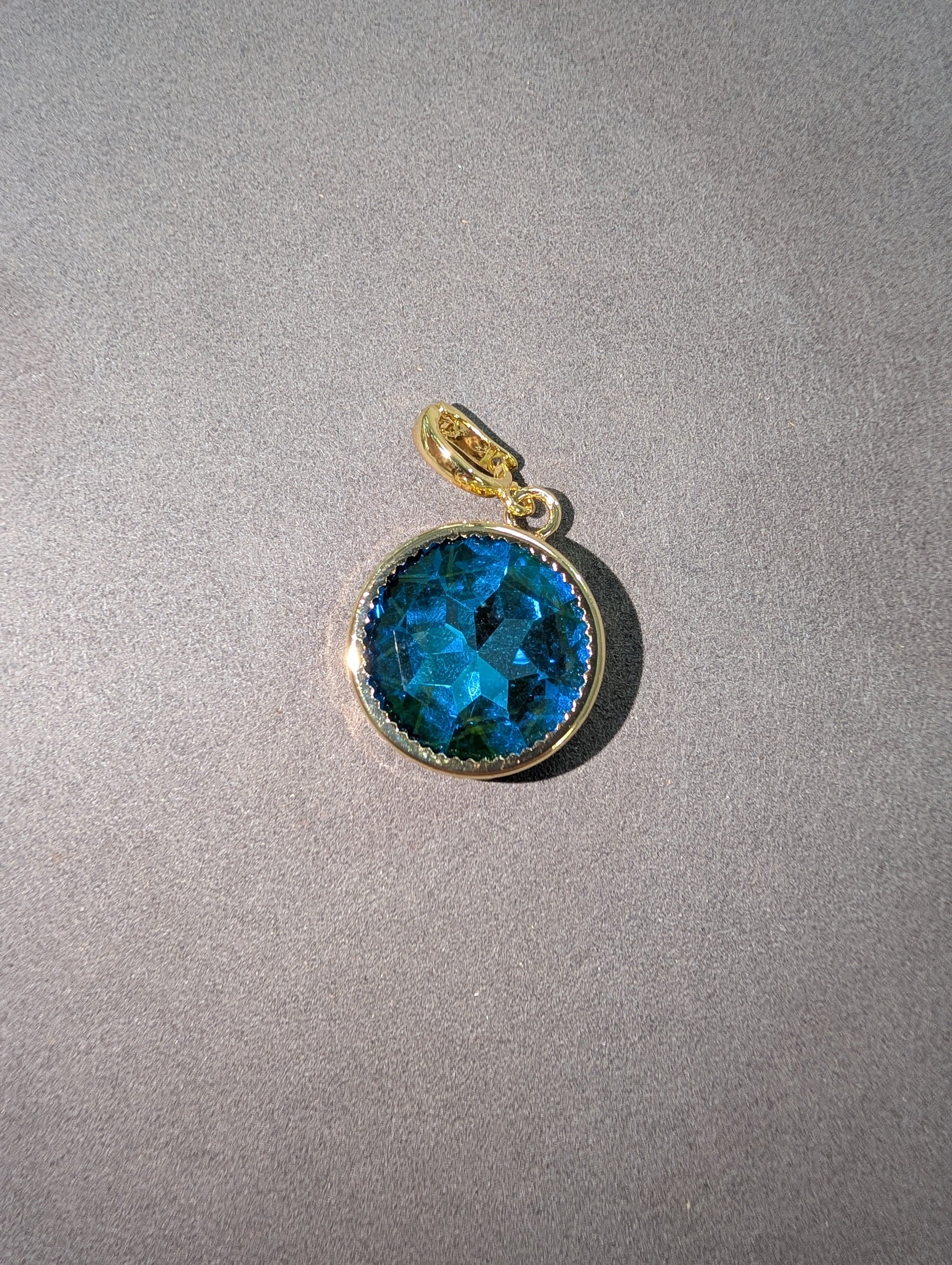 Wafa Round Crystal Charm in Blue Topaz - large faceted round blue topaz crystal in gold milgrain bezel setting with gold bail