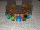 Pre Order WaFa 5-Stone Crystal Cuff Bracelet — green: five mixed teal, emerald green, and blue-violet AB cushion-cut crystals in gold prong settings on wide gold cuff