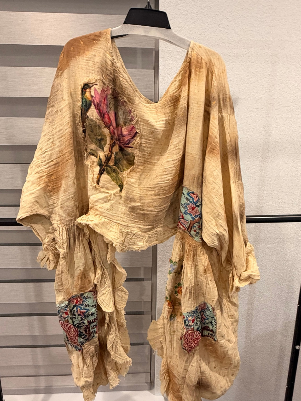 A Rare Bird Golden Songbird Patchwork Ruffle Top in golden beige with floral patches and cascading ruffles, front with hummingbird detail