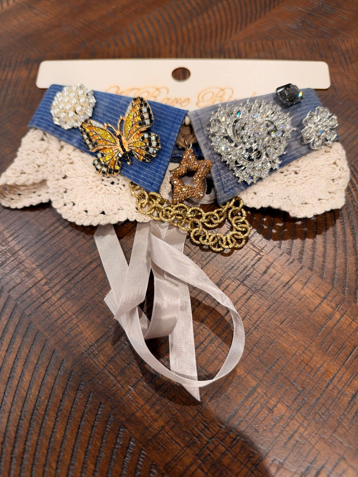 Blue and gray fabric with a golden butterfly, ornate silver-tone sparkling medallion, and pearl-look accents.