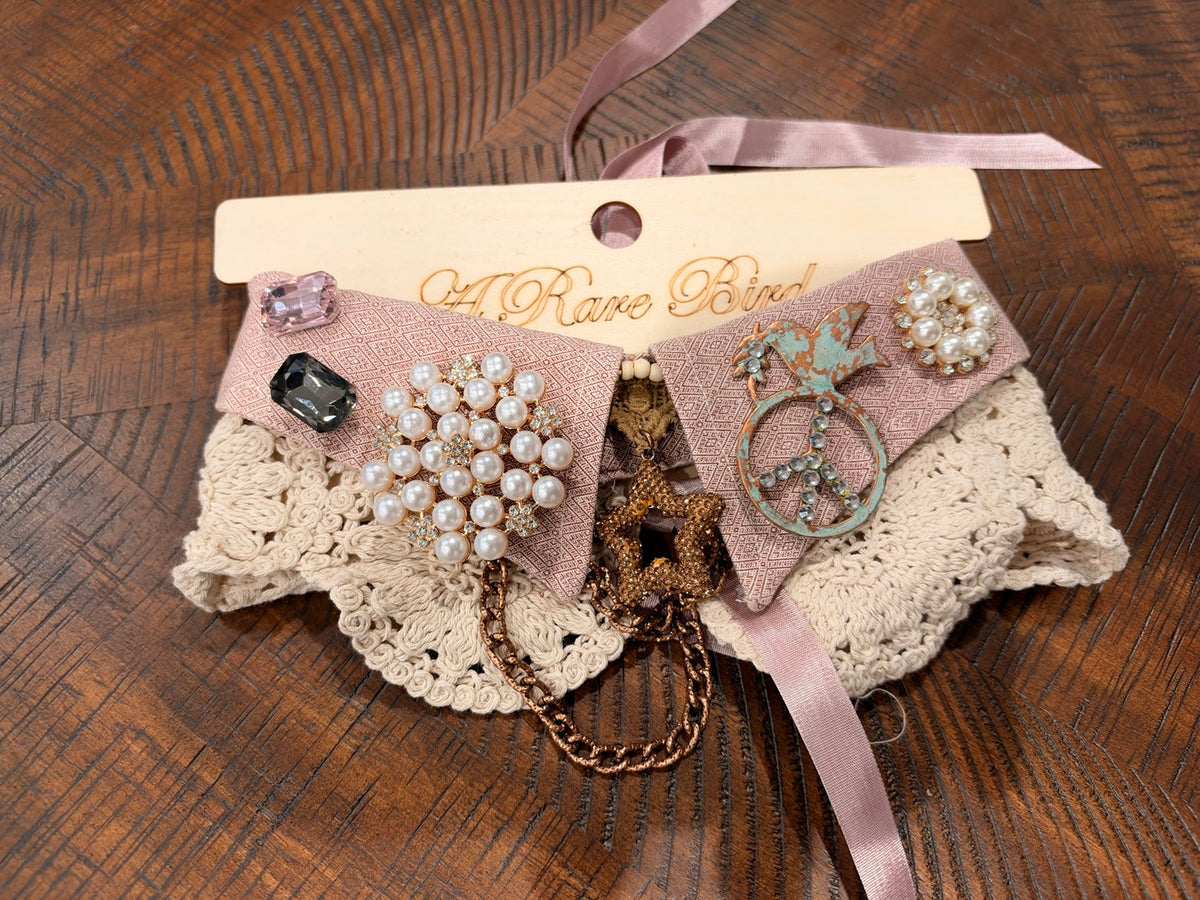 Dusty rose patterned fabric with pearl-look clusters, a turquoise-tone bird and peace-sign ornament, and a star pendant.