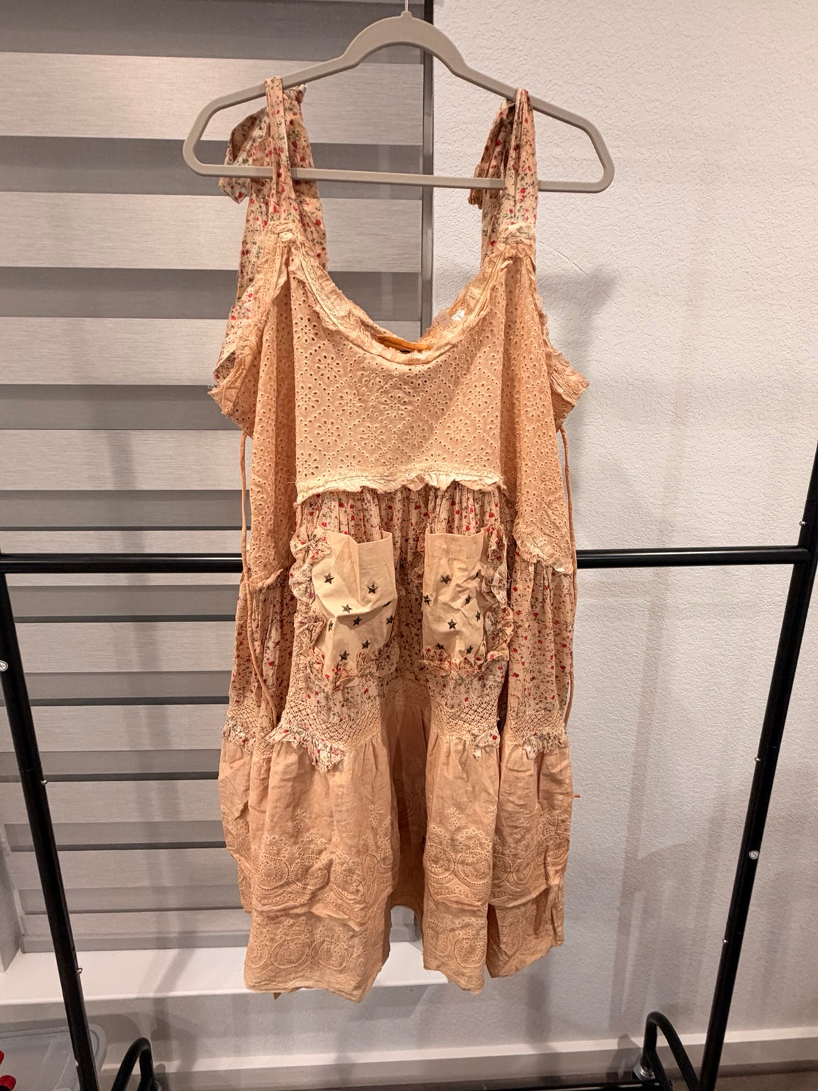 A Rare Bird peach floral eyelet dress with tie shoulders, tiered skirt, and star-print front pockets, front view