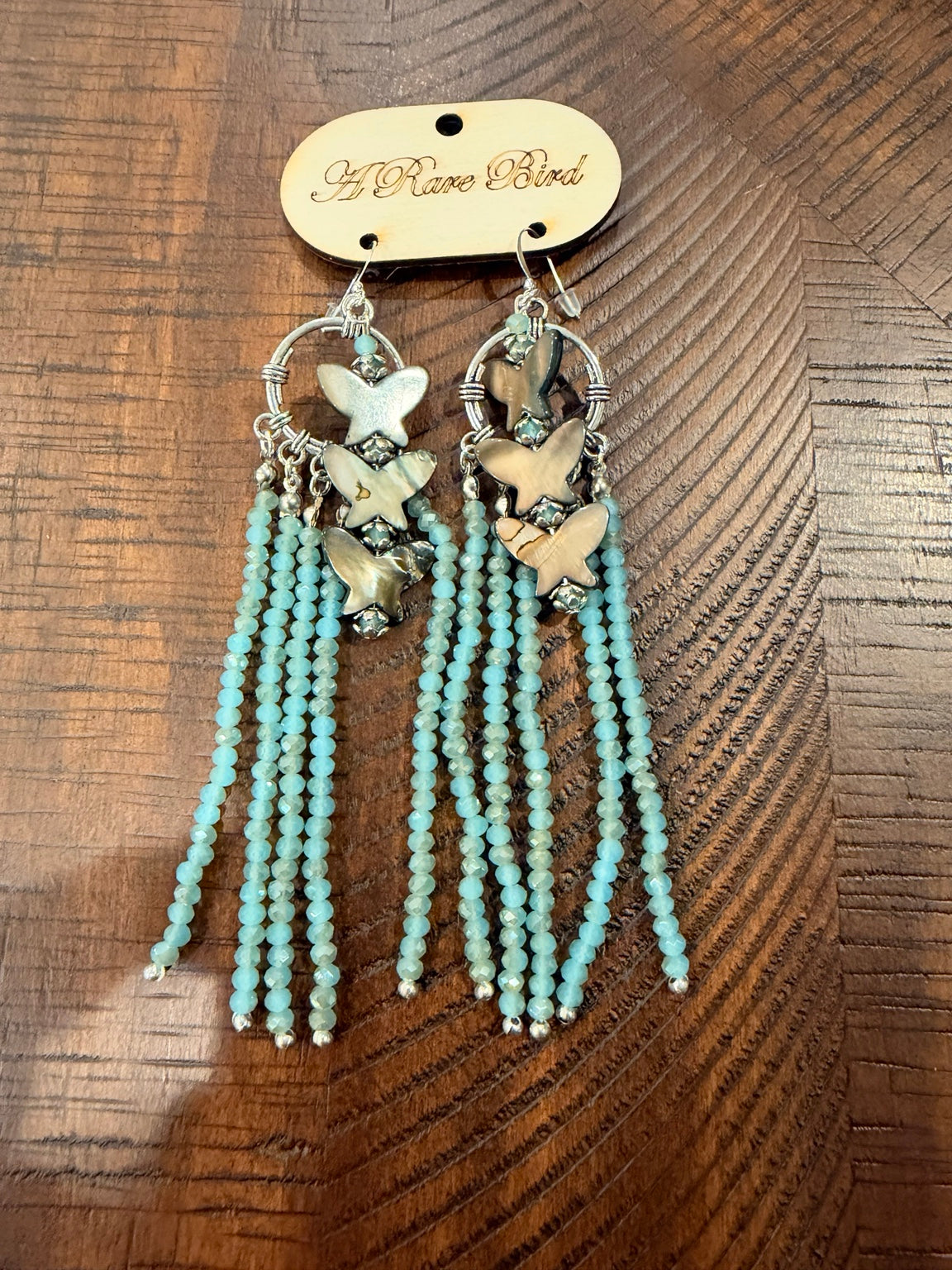 A Rare Bird aqua beaded fringe earrings with pearlescent butterfly shapes and silver-tone hoops