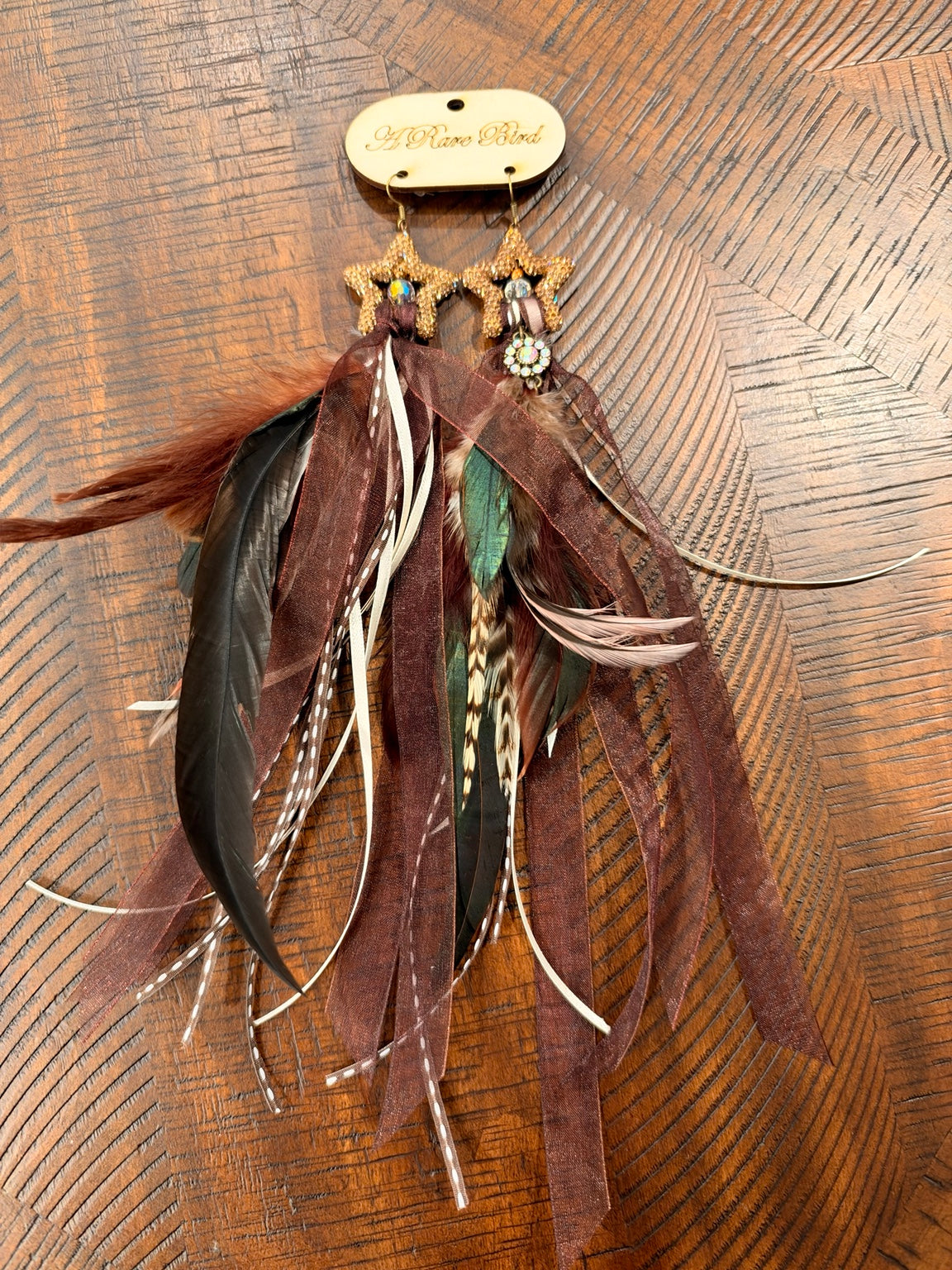A Rare Bird sparkling gold-tone star earrings with brown ribbons and long mixed feathers