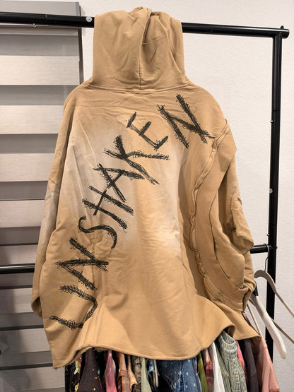 Back of tan A Rare Bird hoodie with UNSHAKEN lettering