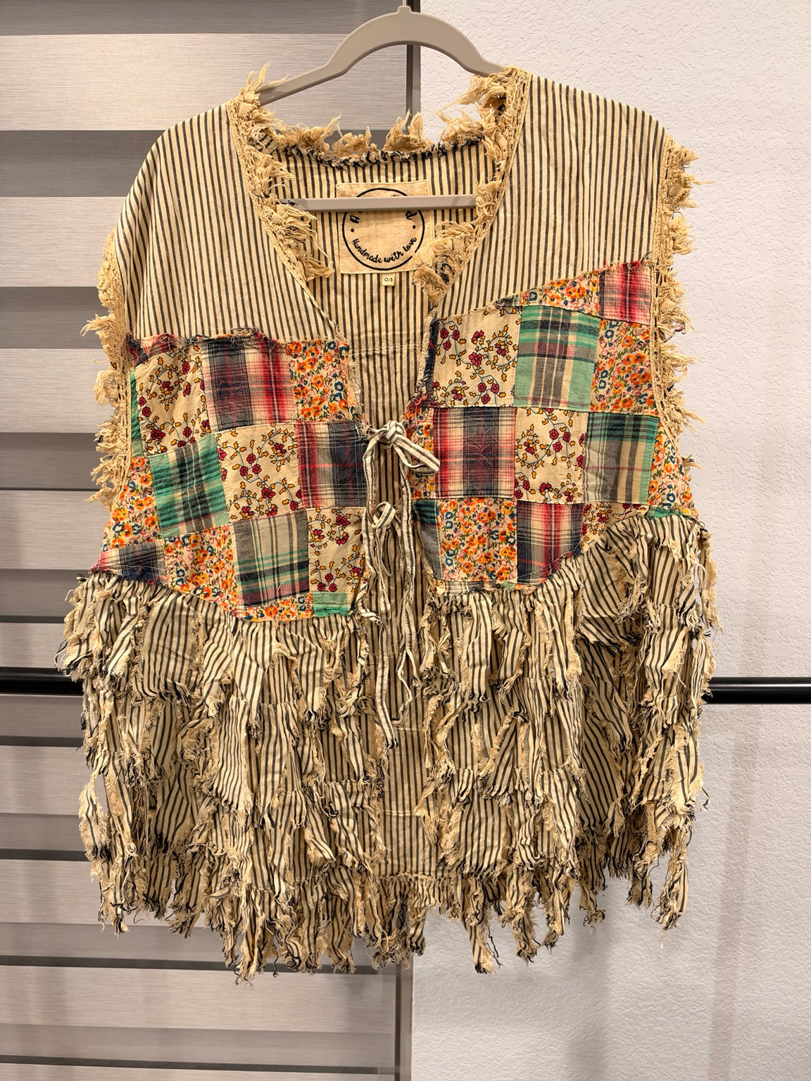 A Rare Bird striped patchwork vest with floral and plaid panels, frayed fringe, and front ties, front view