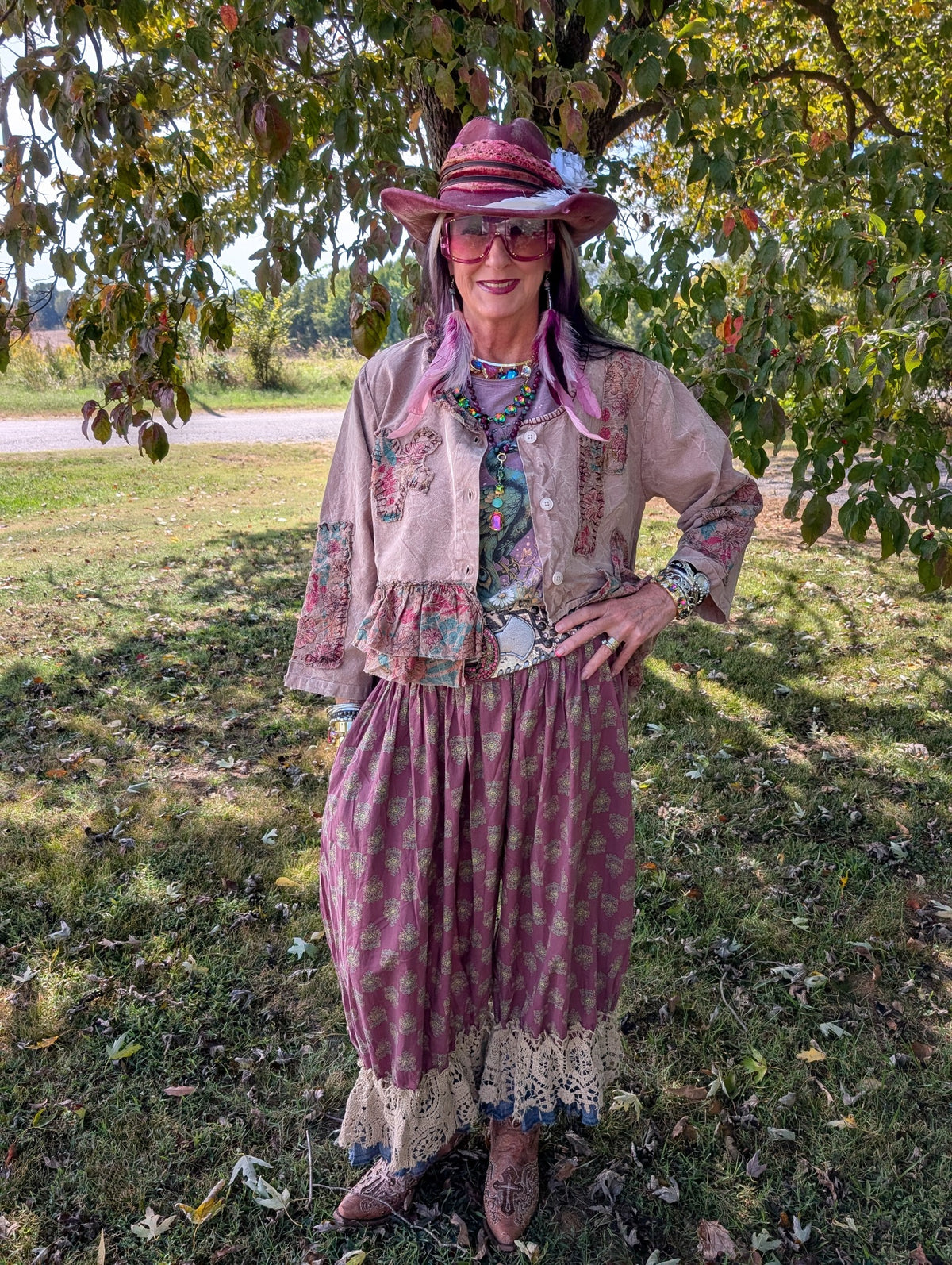 Felecia wearing berry Heirloom Heart Bloomers, the Soft Dune Top, and the Royal Feathers Soft Journey Tee beneath a leafy tree.