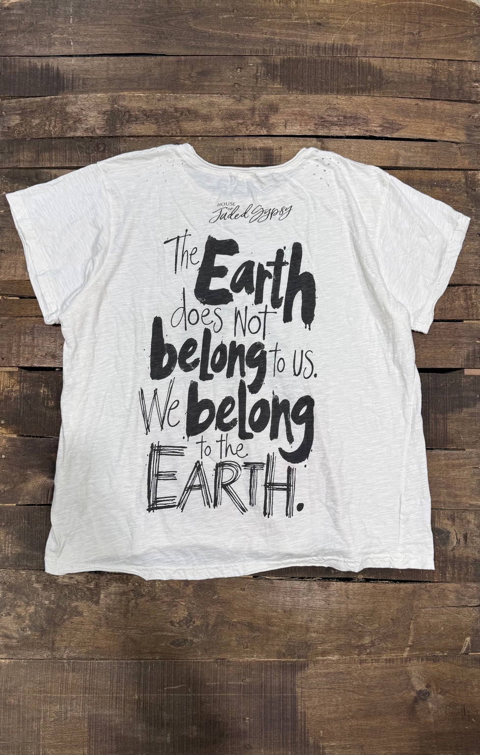 House of Jaded Gypsy white graphic tee, back with The Earth does not belong to us message