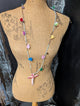 Long beaded necklace with colorful tassels and a pink fabric cross pendant