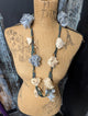 Design B cloth flower necklace with blue and cream flowers on a teal printed fabric strand
