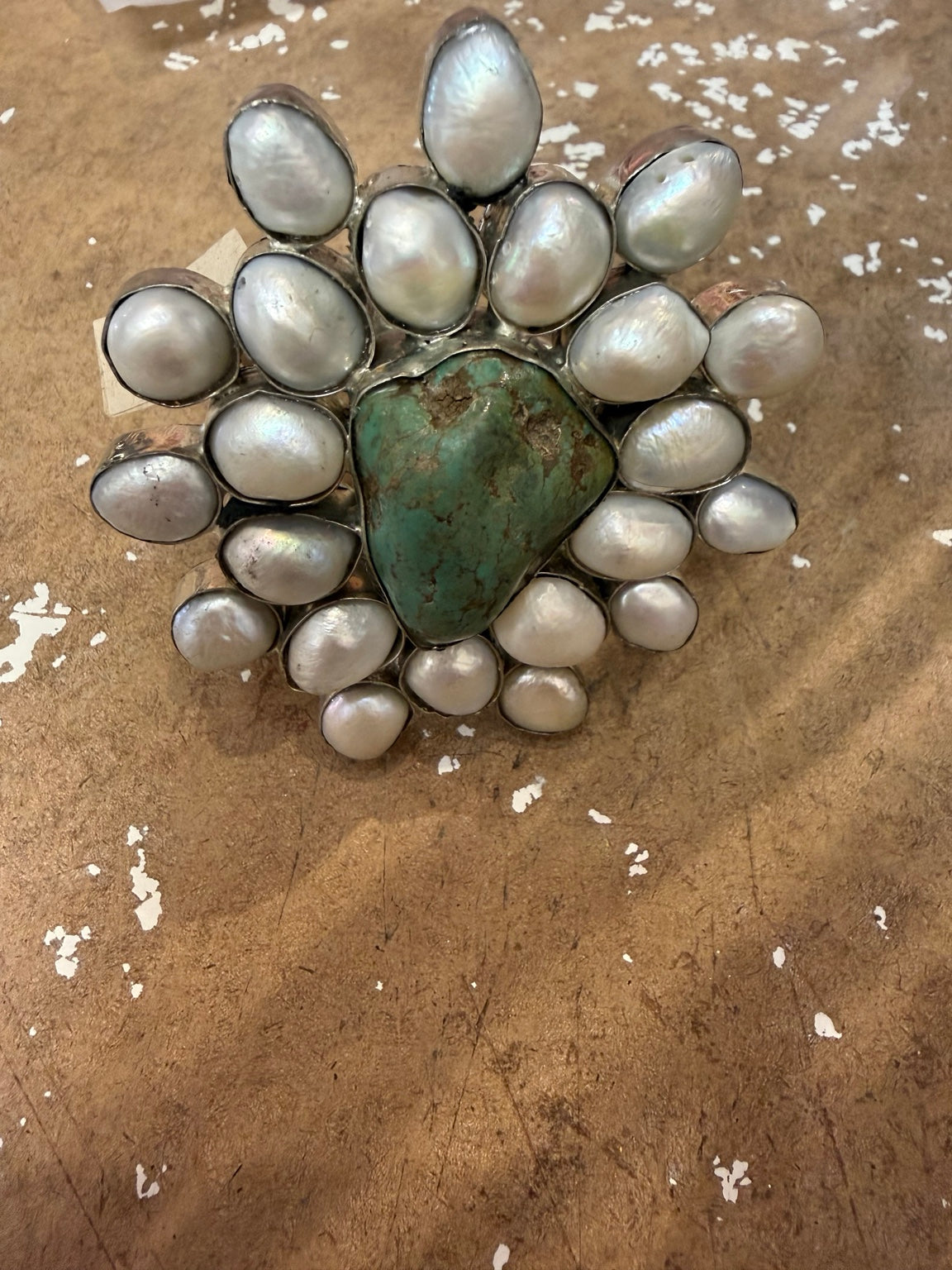 A Rare Bird statement cuff with a green-blue center stone, iridescent white accents, and silver-tone setting