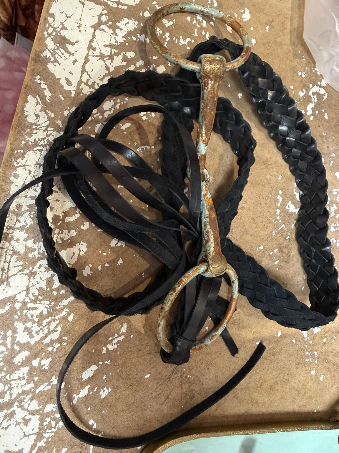 A Rare Bird black braided belt with distressed horse-bit hardware and long ties