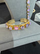 Gold-tone open cuff with round pink, lavender and iridescent crystals
